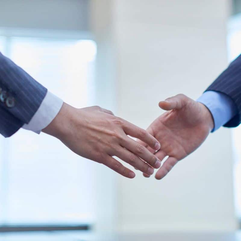 Business handshake symbolising successful Community and Stakeholder Engagement partnership in a professional setting with blurred office background.