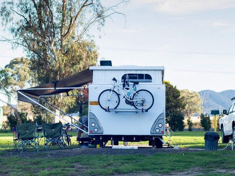 Caravan setup with bike and camping chairs in rural setting, showing key site features for caravan park planning in Australia